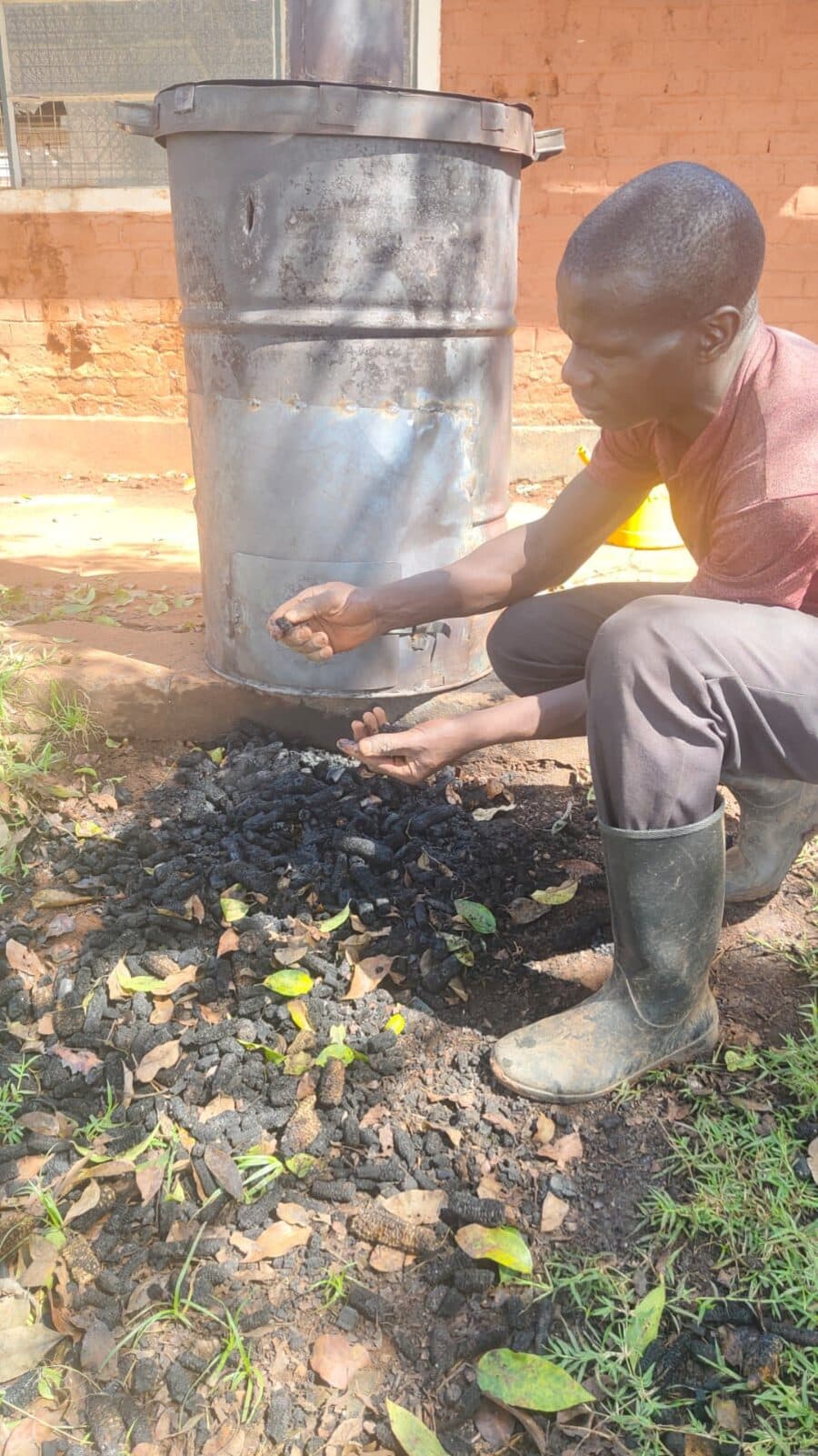 A trainer holding finished black biochar pieces in both hands