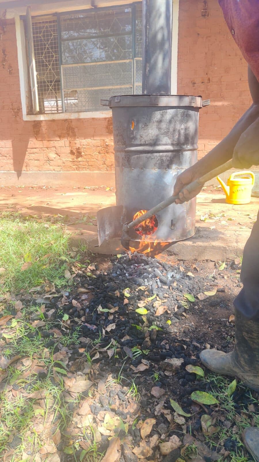 Glowing char being raked out of the kiln door with a shovel