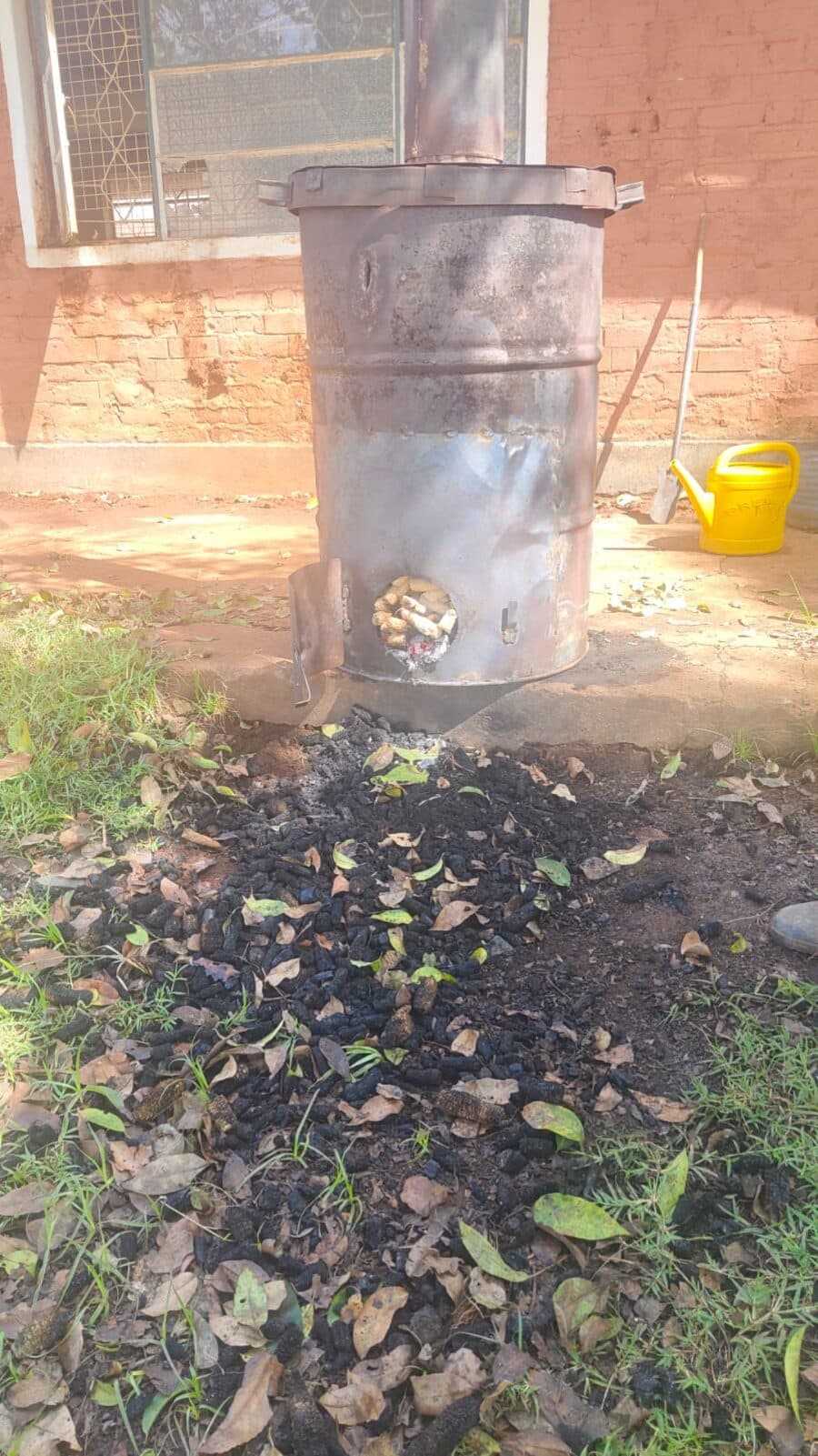 Maize cobs visible through the kiln door with charred cobs spread in front