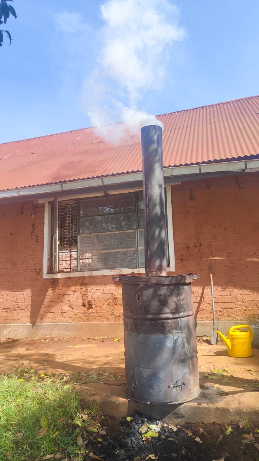 A drum kiln producing biochar, with smoke rising from its chimney