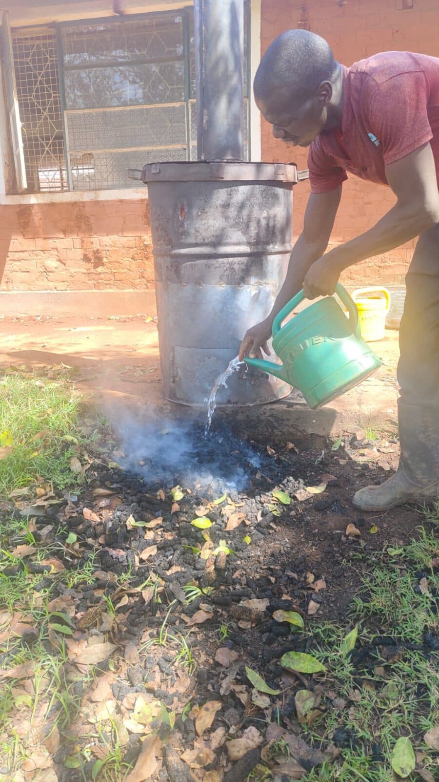 Water being poured from a watering can onto hot char, producing steam